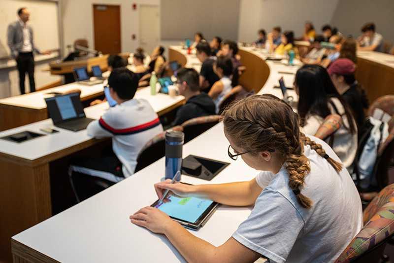 Photo of a Weatherhead School of Management classroom at Case Western Reserve University, with a focus on a student using a tablet device